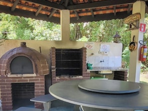 A brick oven and a table with a circular top, likely for food preparation or serving. - VELINN Pousada Lua e Sol (Santo Antônio do Pinhal)