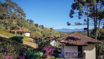 Una propiedad en una ladera con varias construcciones, incluyendo una casa con balcón y una estructura más pequeña con techo de tejas.