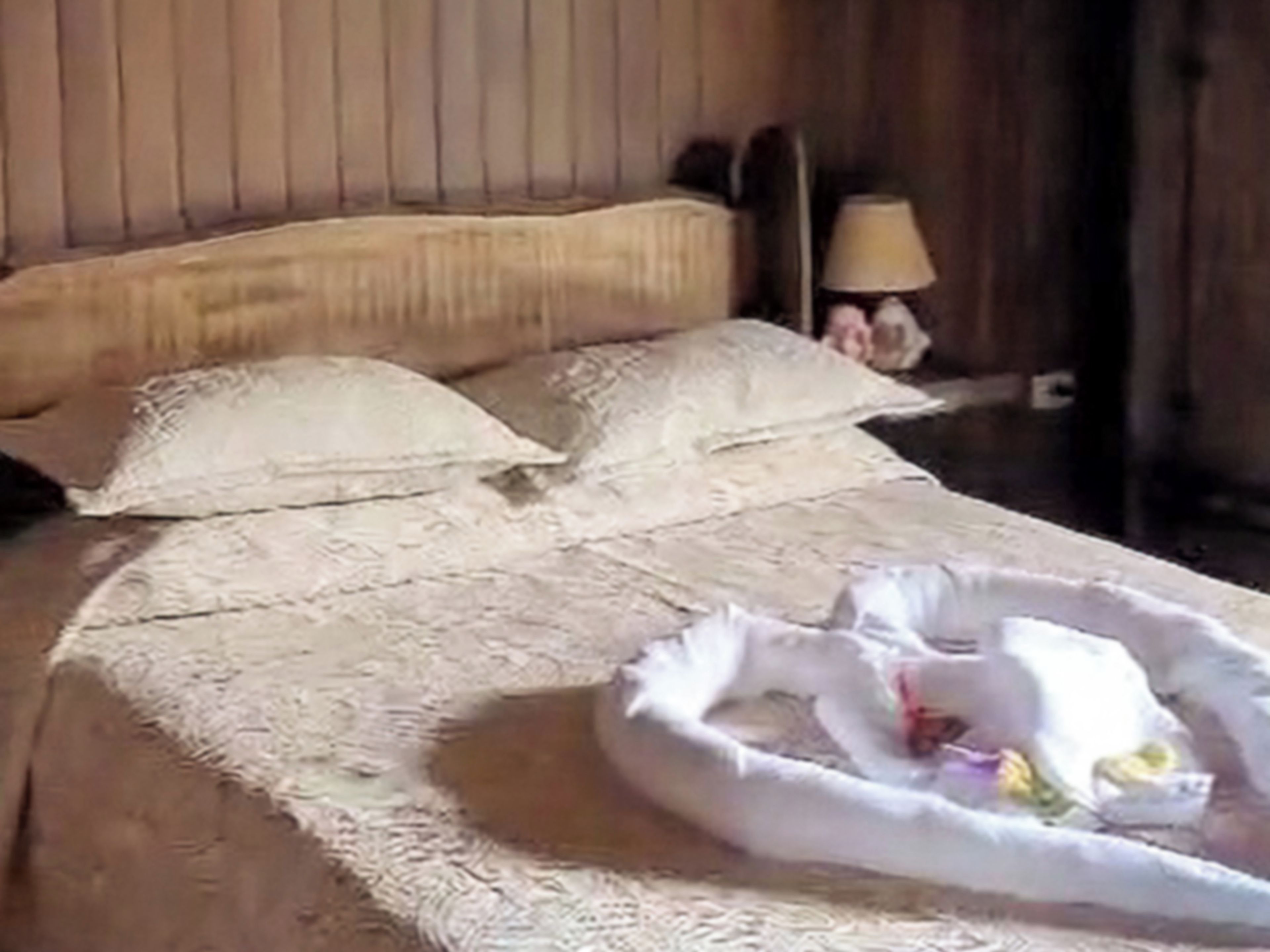 Una cama con una colcha blanca, almohadas y una almohada decorativa con forma de cisne.