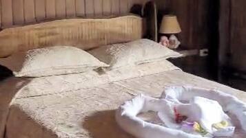 Una cama con una colcha blanca, almohadas y una almohada decorativa con forma de cisne.