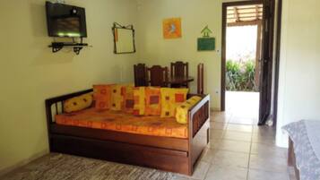 A bedroom with a bed, a TV, a chair, and a small table.