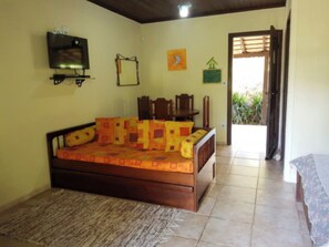 A bedroom with a bed, a TV, a chair, and a small table. - VELINN Pousada Lua e Sol (Santo Antônio do Pinhal)