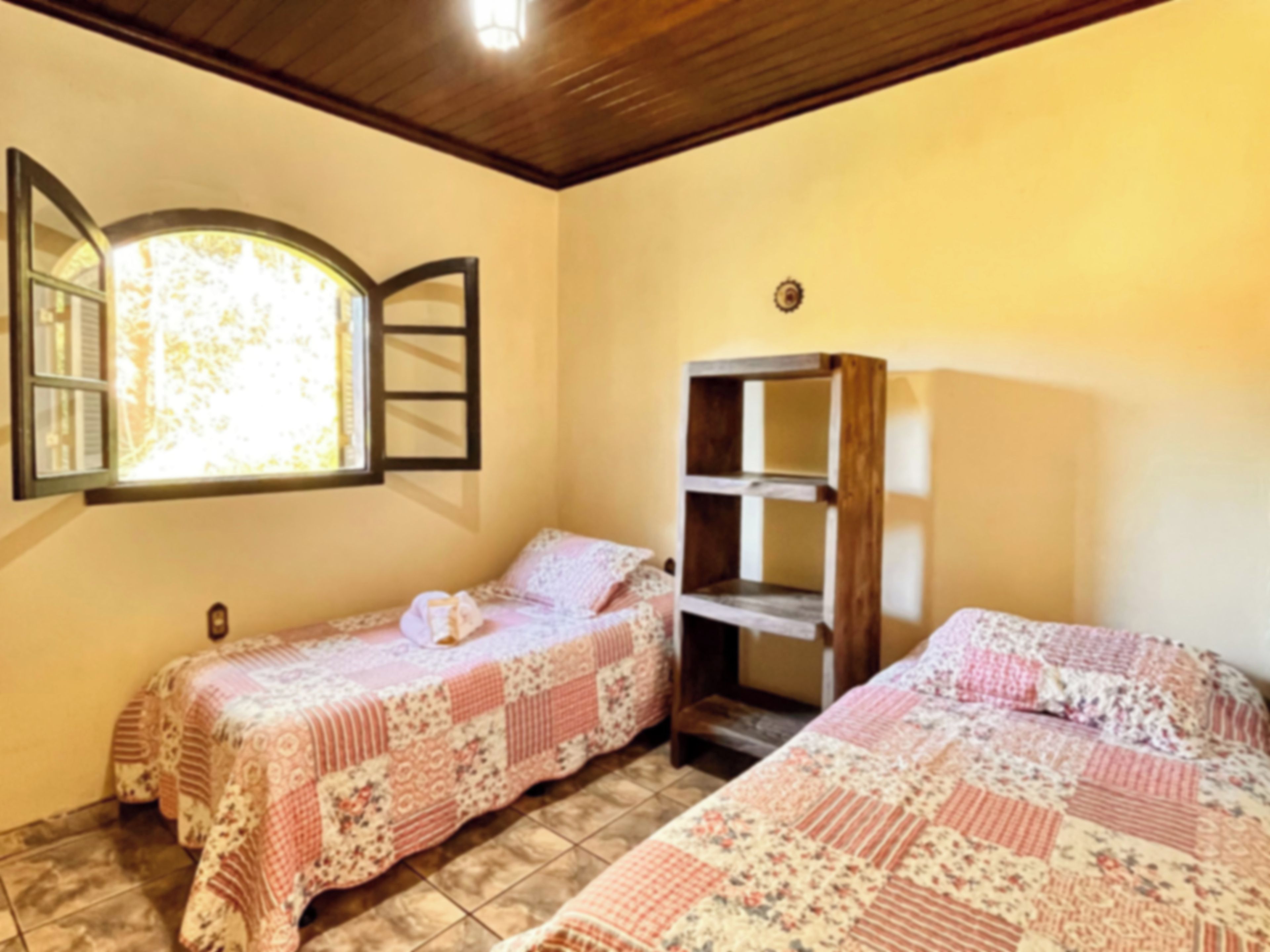 A room with two beds, a window with a view, and a wooden shelf.