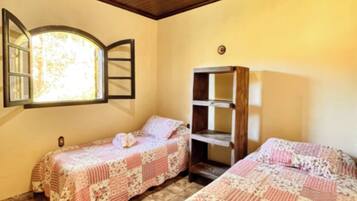A room with two beds, a window with a view, and a wooden shelf.