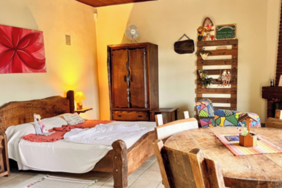 A cozy room with a wooden bed, a dining table, and a fireplace.