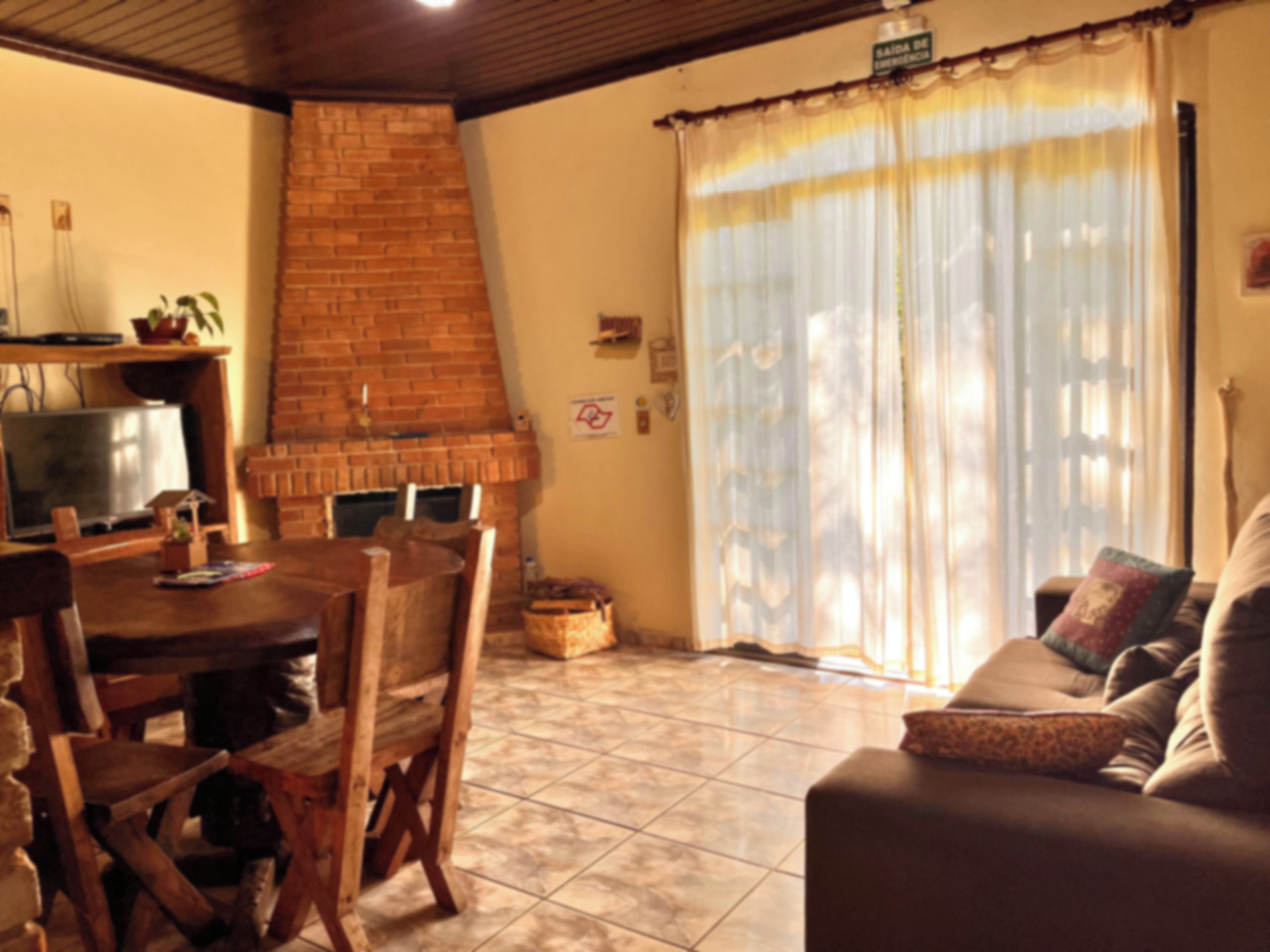 A living room with a brick fireplace, a television, a sofa, and a dining table with chairs.