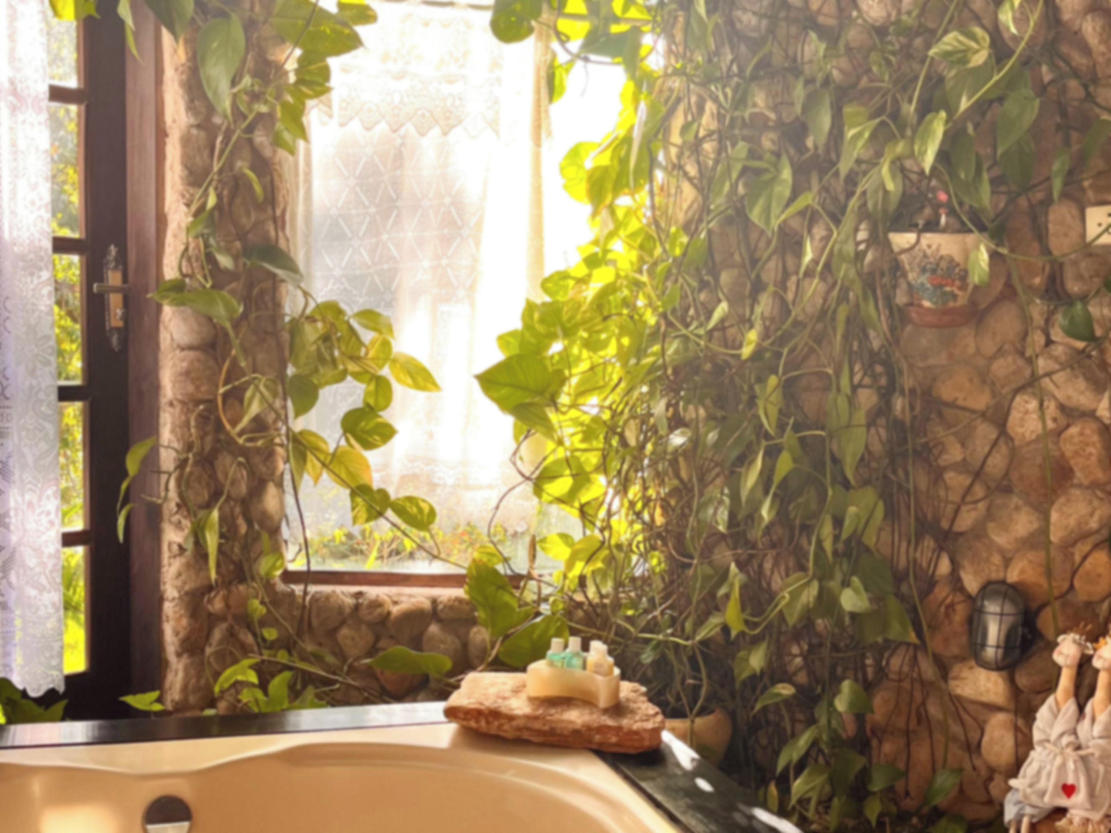 A bathroom with a bathtub, a window with a lace curtain, and a wall covered in greenery.