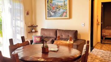 A dining area with a round wooden table, chairs, a sofa, and a painting on the wall.