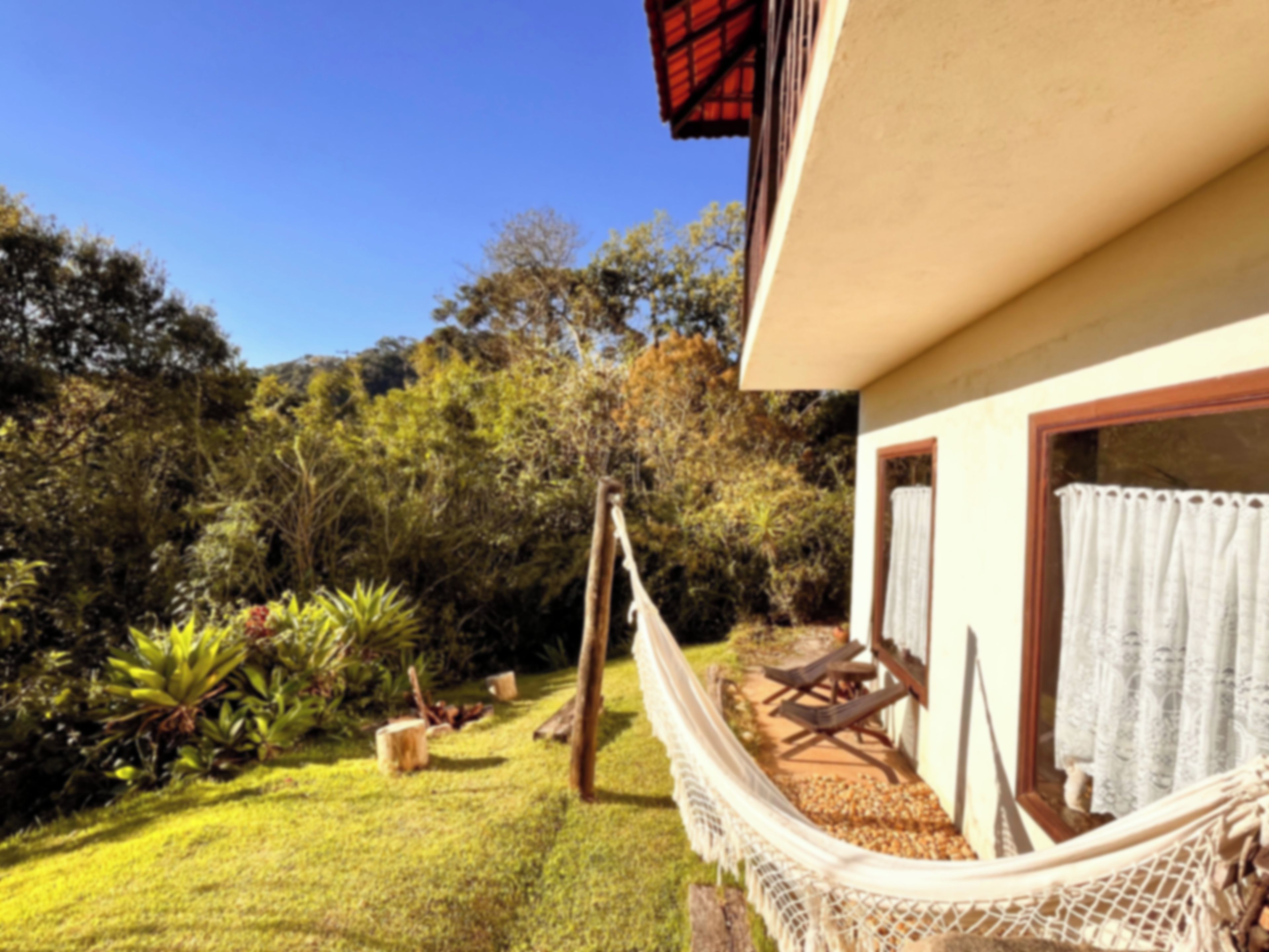 Uma rede presa a um edifício, com vista para um jardim e árvores.