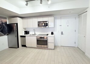 A modern kitchen with white cabinets, stainless steel appliances, and a tiled floor. - Stylish Modern 1BR |Private Balcony & Beach Access (Hallandale Beach)