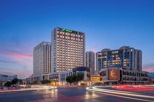 Un hotel de varios pisos con un llamativo letrero de Holiday Inn, rodeado de otros edificios altos.