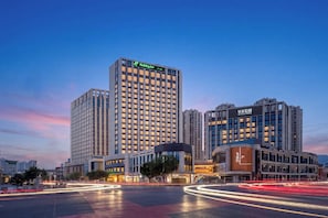 Un hôtel à plusieurs étages, reconnaissable à son grand panneau « Holiday Inn », entouré d’autres immeubles de grande hauteur.