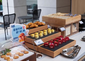 A buffet with various food items including pastries, desserts, and a sign indicating a special offer.