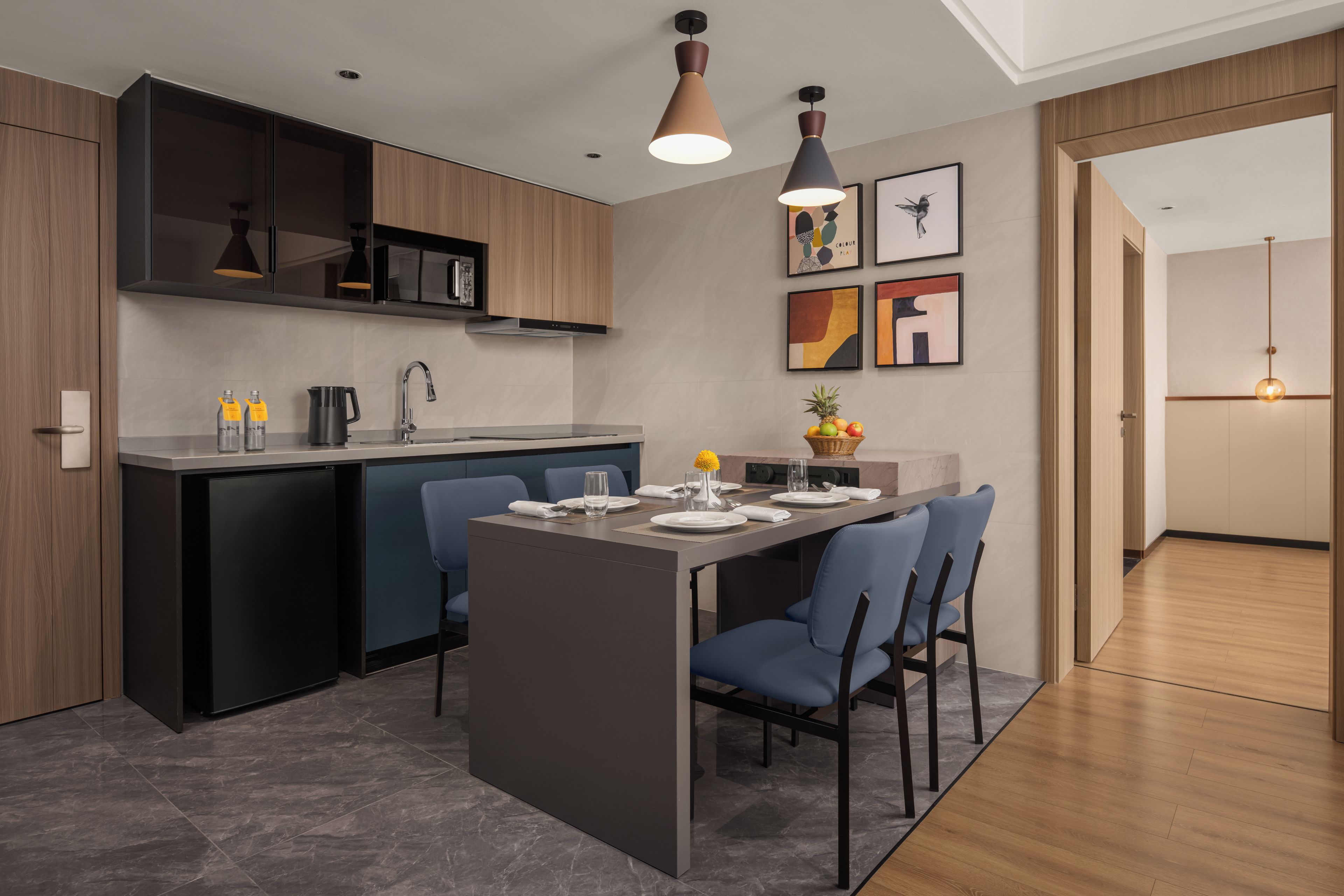 A modern kitchen with a central island, dark cabinetry, and pendant lighting.