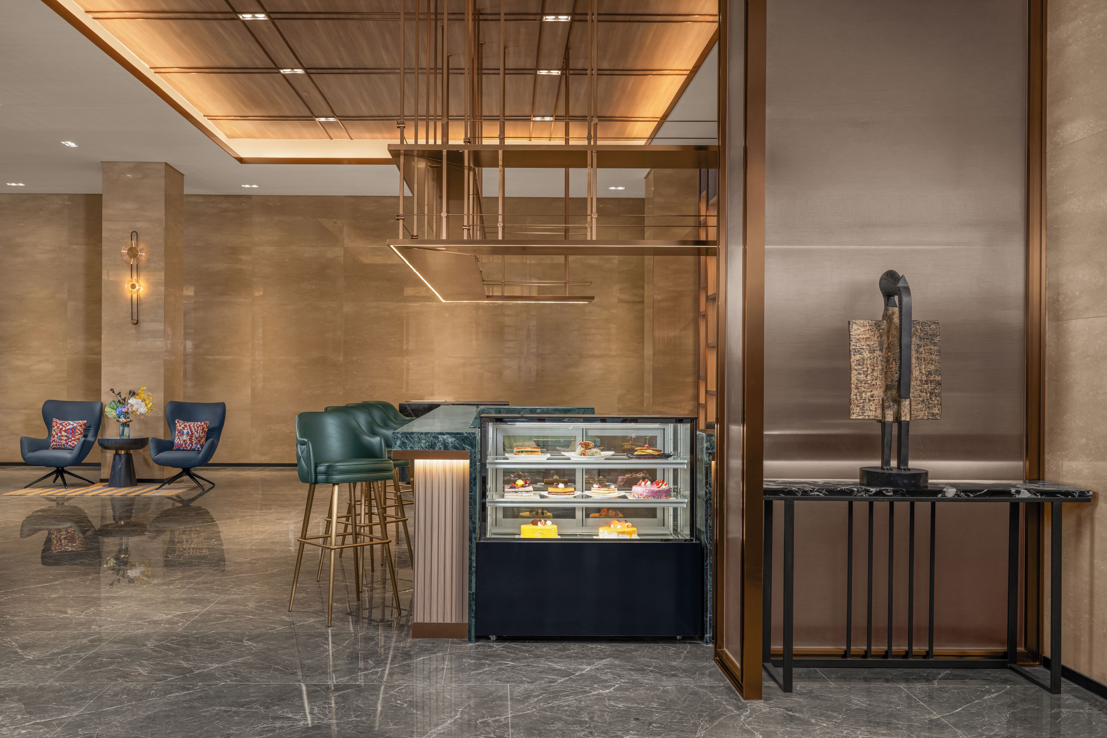 Un interior moderno con zona de bar, asientos y una vitrina con postres.