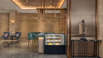 Un interior moderno con zona de bar, asientos y una vitrina con postres.