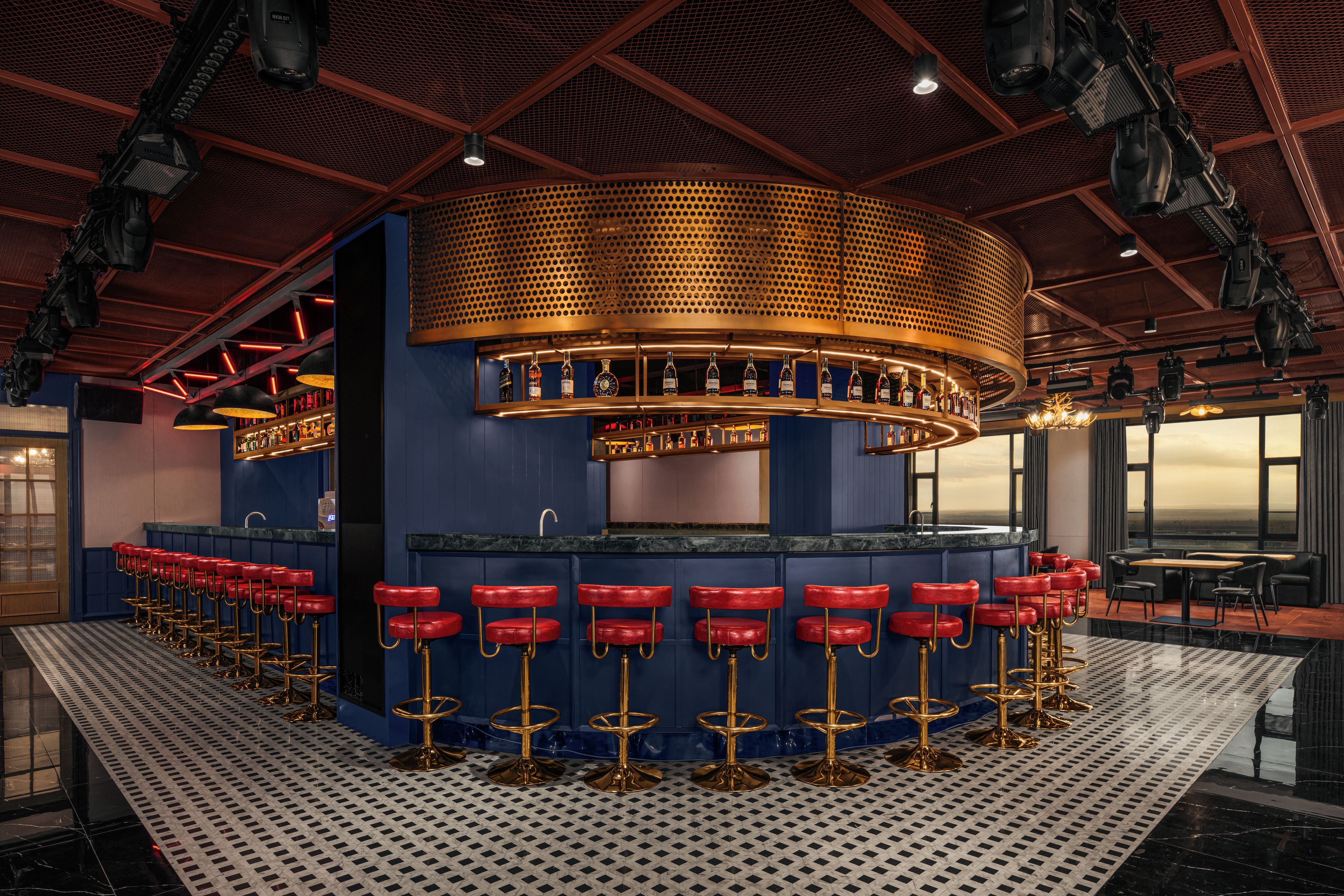 Una zona de bar con varios taburetes y una barra circular.