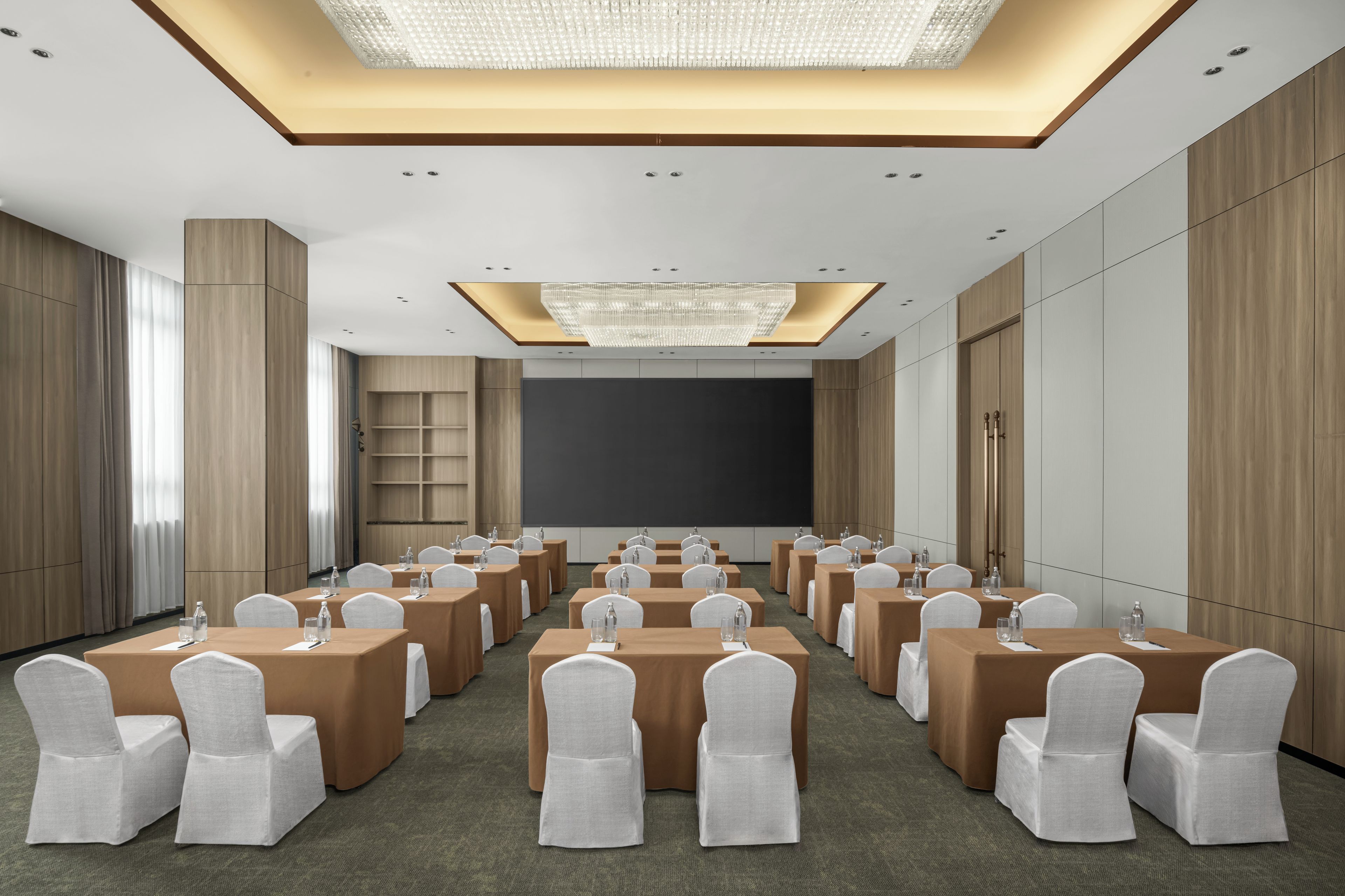 A conference room with a large screen, multiple tables, and chairs.