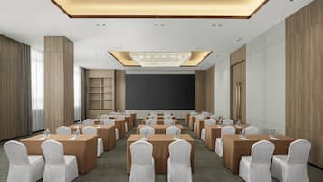 A conference room with a large screen, multiple tables, and chairs.