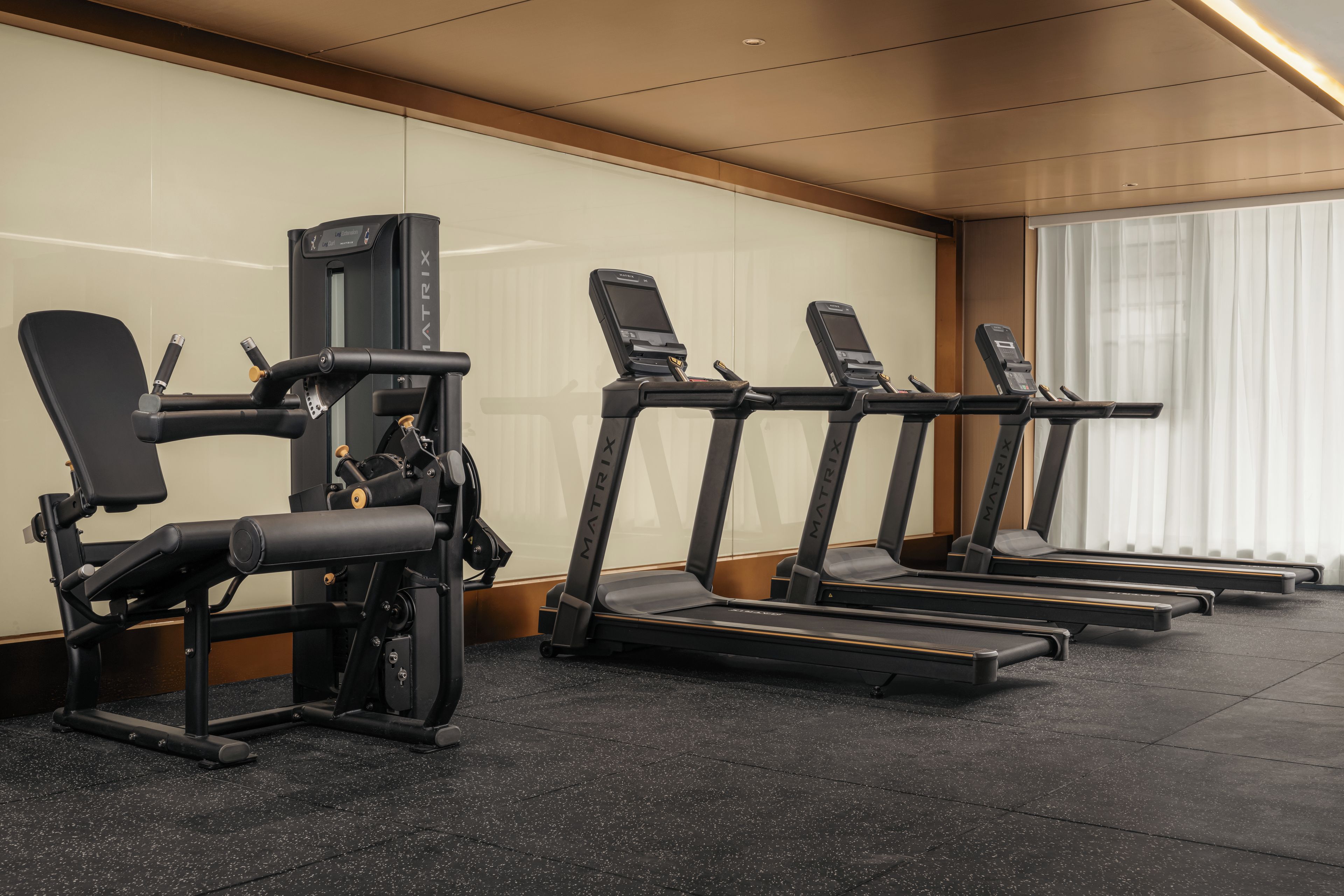 Un gimnasio con cintas de correr, una máquina de prensa de piernas y un banco para press de banca.