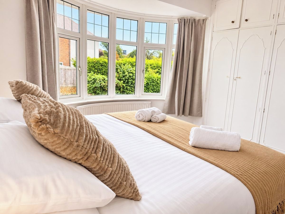 Une chambre d’hôtel avec un lit, une fenêtre avec des rideaux, une vue sur la verdure et une armoire.
