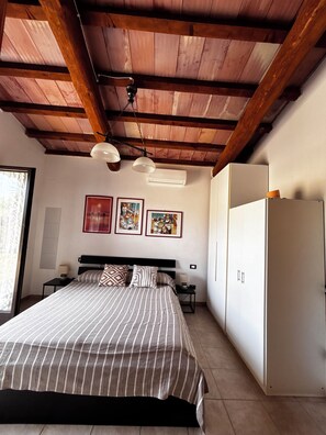 A bedroom with a bed, bedside tables, a wardrobe, and a ceiling fan. - La Quercia Two-Room Apartment in the Heart of the Maremma (Grosseto)