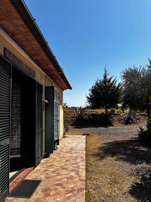 A building with a tiled entrance, a brick roof, and a clear sky. - La Quercia Two-Room Apartment in the Heart of the Maremma (Grosseto)