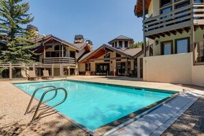 A pool area with a clear blue pool, lounge chairs, and a building with a modern architectural style. - Abode at Winterhaven, hot tub pool, Deer Valley (Park City)