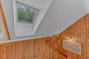 A wooden staircase with a skylight and a wall-mounted ski rack. - Cozy Condo at Waterville Estates (Thornton)