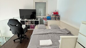 Ett sovrum med en säng, ett skrivbord, en stol, en tv och ett fönster.
