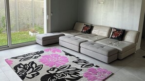 Ein modernes Wohnzimmer mit einer Eckcouch, einer großen Schiebetür aus Glas und einem gemusterten Teppich.