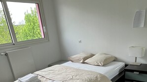 Ett sovrum med en säng, ett nattduksbord och ett fönster.