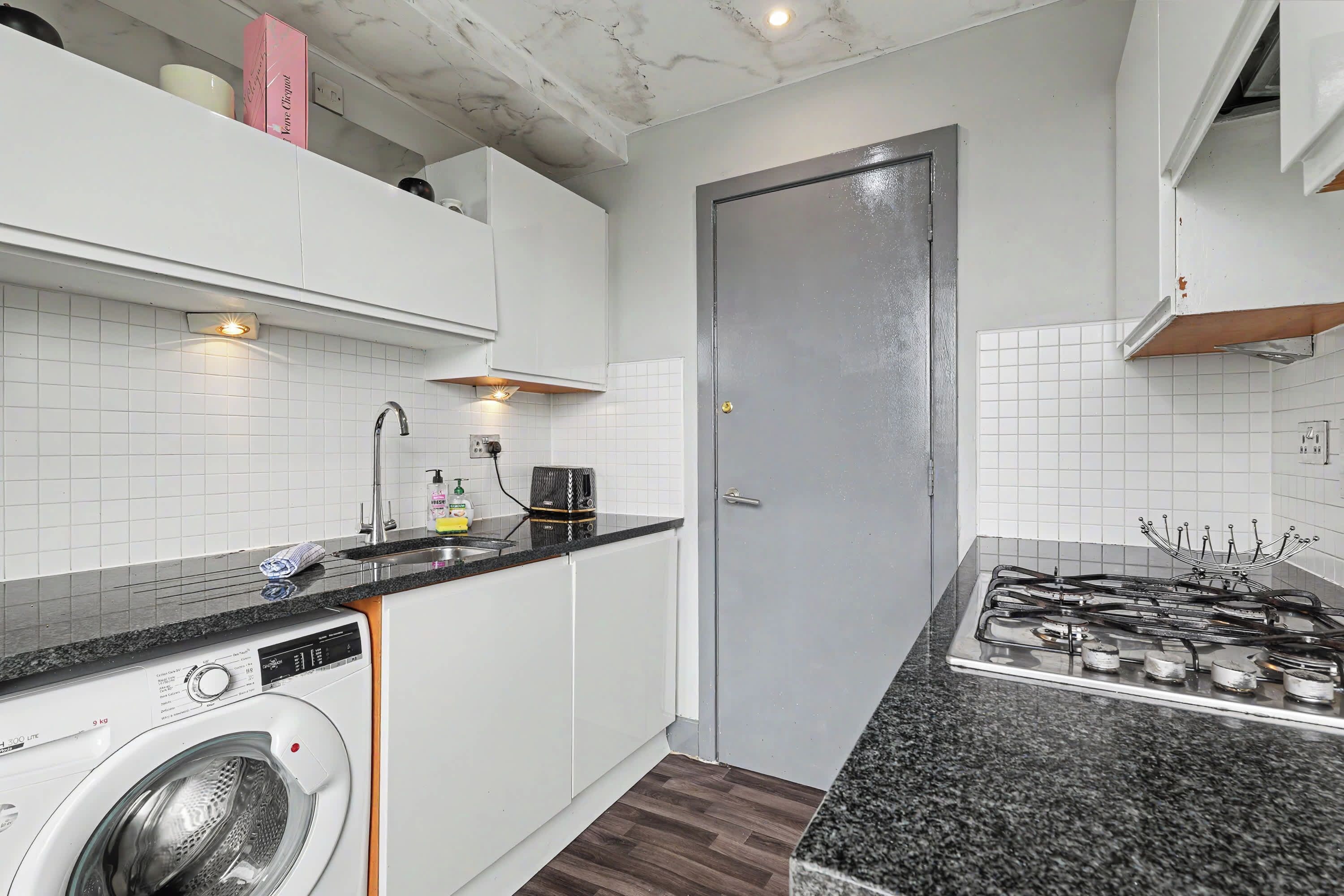 Una cocina compacta con lavadora, cocina a gas y una puerta.