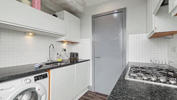 Una cocina compacta con lavadora, cocina a gas y una puerta.