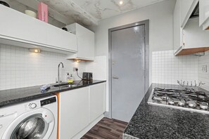 Una cocina compacta con lavadora, cocina a gas y una puerta.