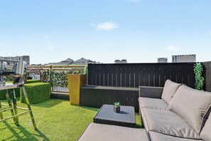 Una terraza en la azotea con un sofá, una mesita y una silla.