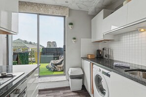 A modern kitchen with a built-in washing machine, a sink, and a window overlooking a garden.