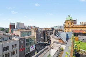 A cityscape with a mix of modern and historic architecture, including a prominent building with a green dome and a sign for 'Bank of Scotland.'