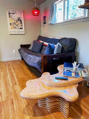 Una sala de estar con un sofá, una mesa de centro de madera única y un cartel en la pared.