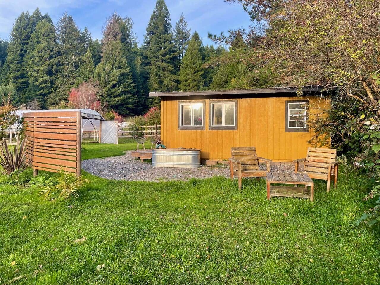 A wooden cabin with a small patio area, a hot tub, and outdoor seating.
