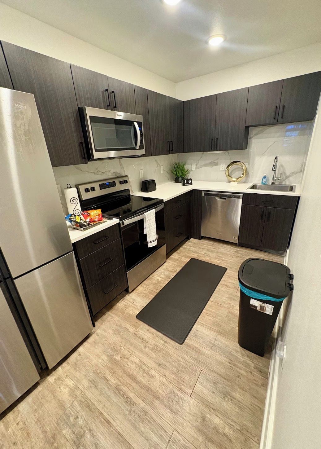 A compact kitchen with dark cabinets, a microwave, a stove, and a dishwasher.