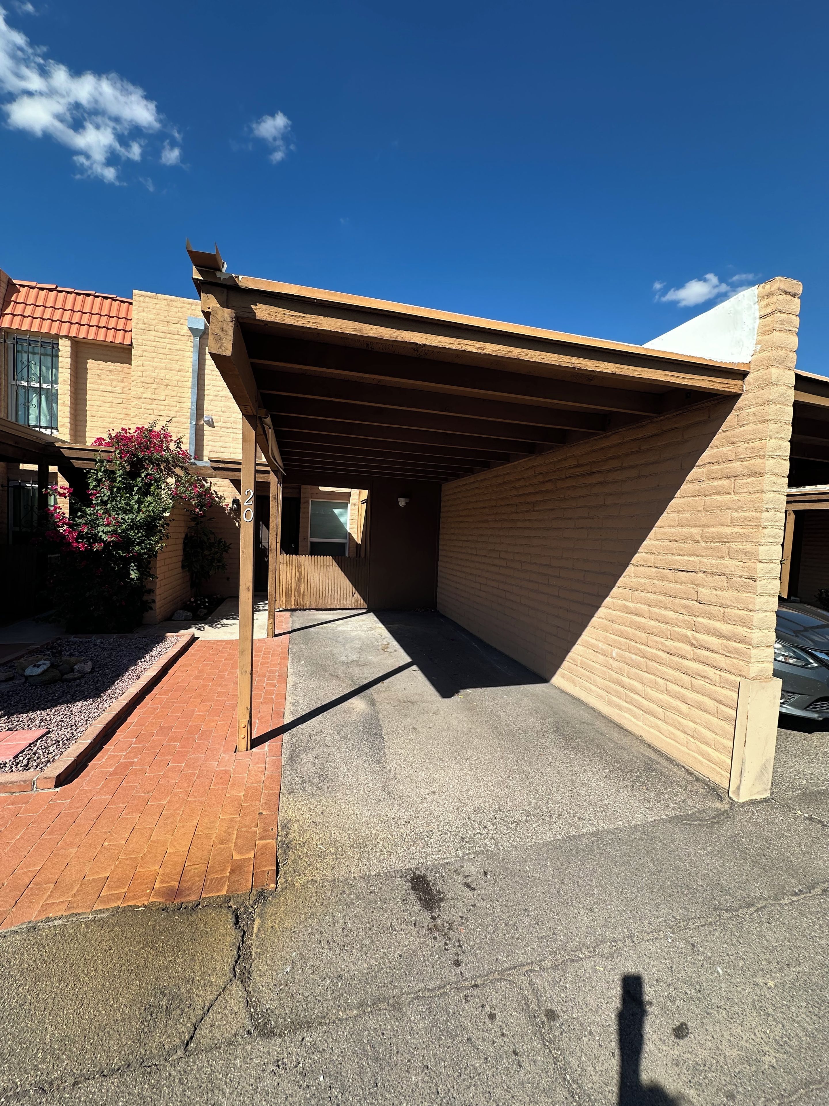 A covered parking area with a brick wall and a wooden roof structure.