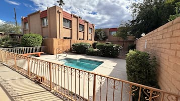 A residential property with a swimming pool, a wooden fence, and a brick building.