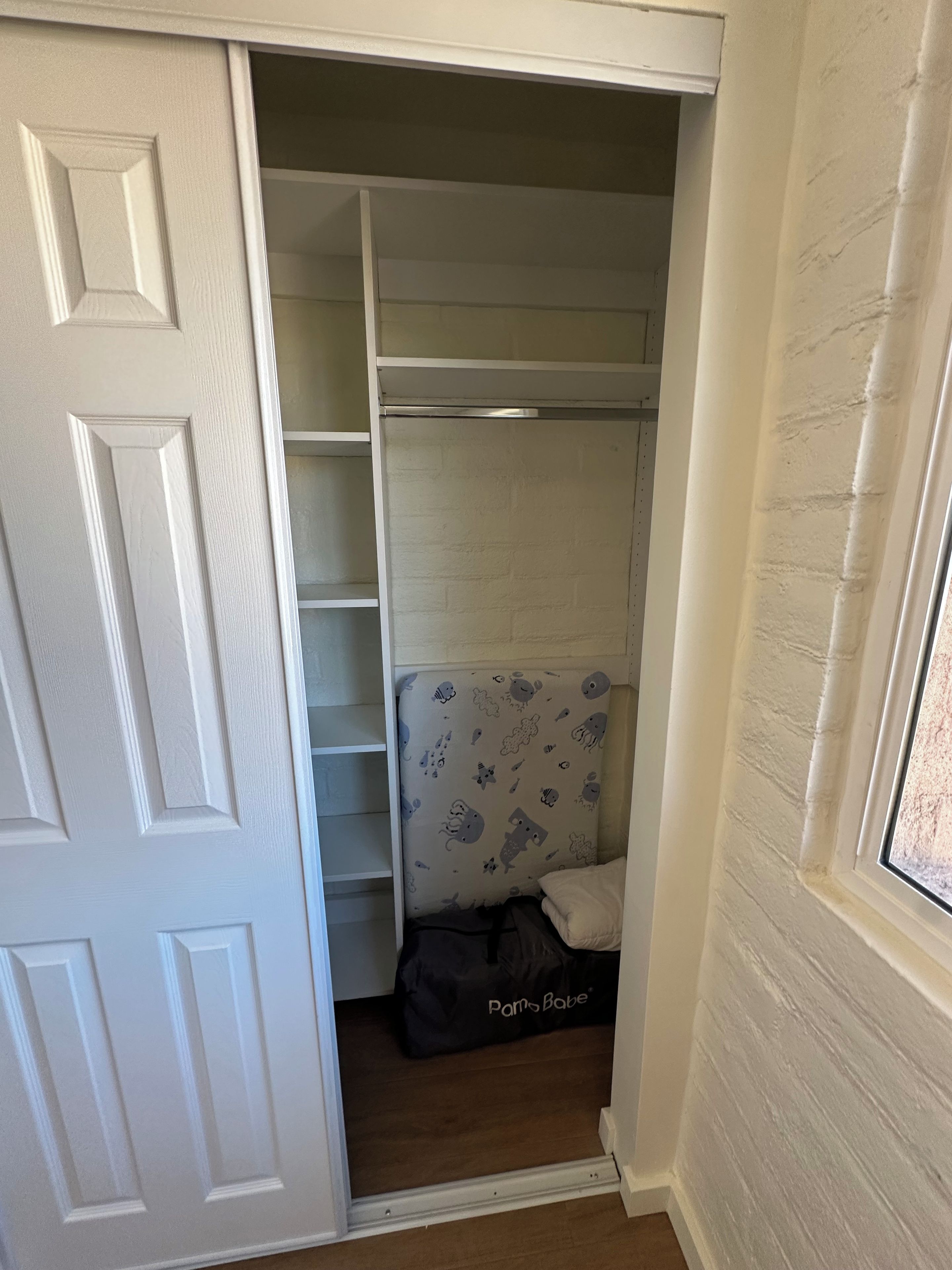 A walk-in closet with white walls, a door, and a window.