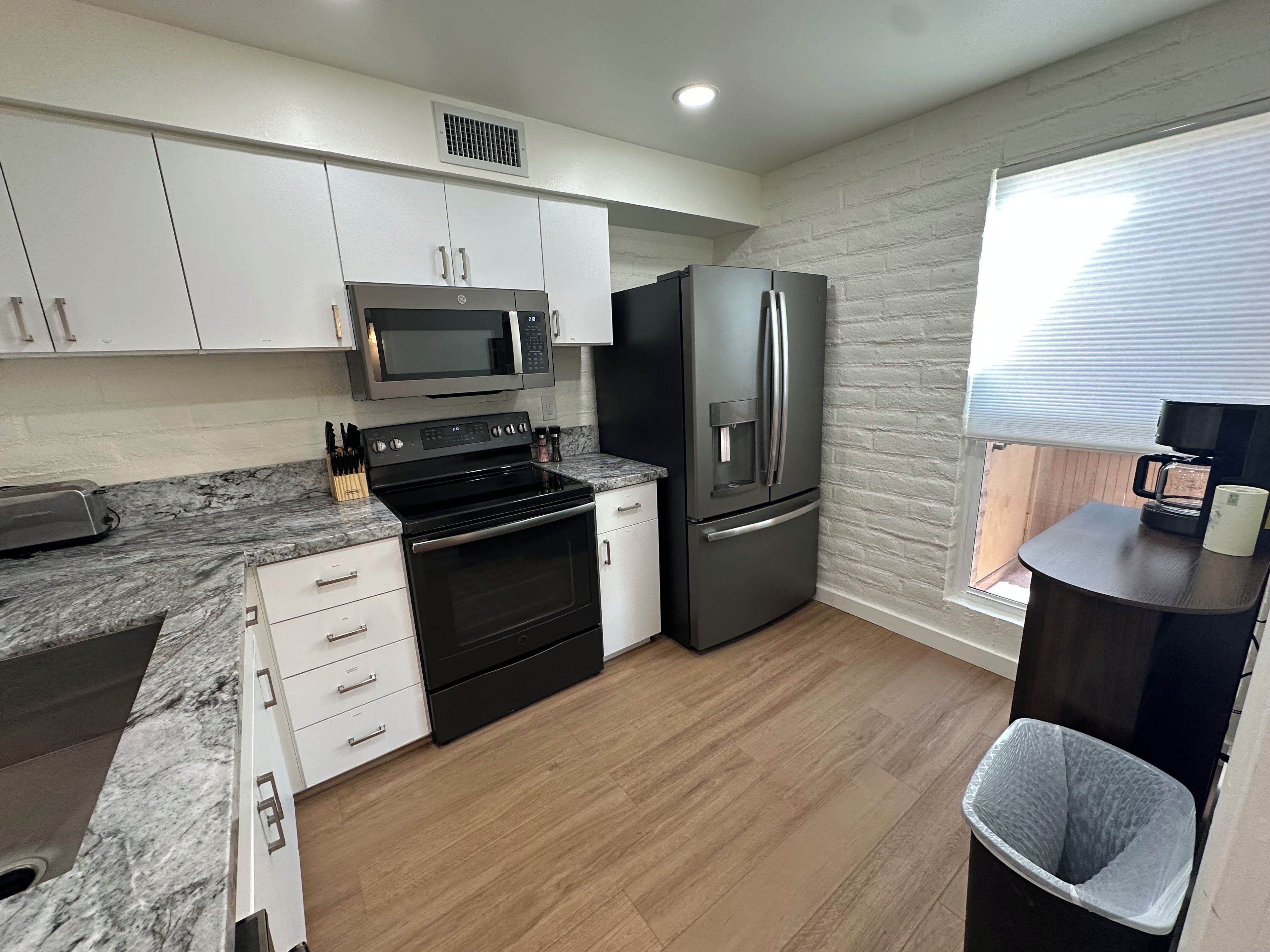 A modern kitchen with white cabinets, a stainless steel refrigerator, a microwave, and a built-in oven.