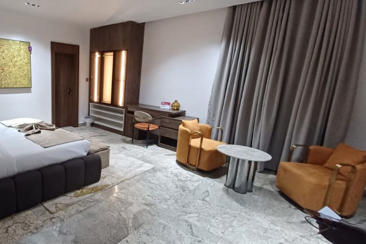 Un salon moderne avec un canapé, une table basse et un fauteuil. Un escalier mène à un niveau supérieur.
