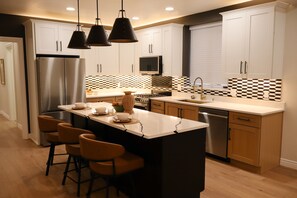 A modern kitchen with a central island, stainless steel appliances, and a patterned backsplash. - 3-bedroom house in delightful Albuquerque Watch the Balloon Fiesta  on the porch (Albuquerque)