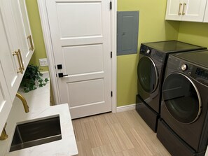 Een wasserette met een witte deur, een wasmachine en een droger.