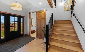 Una escalera de madera que conduce a un segundo piso, un ventanal con vistas al paisaje y una puerta corredera.