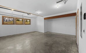 A spacious room with a concrete floor, white walls, and wooden beams. There are three windows with wooden frames. - The Brush Creek Lookout - Home Away From Home (Crested Butte)